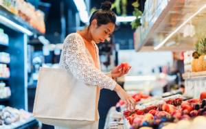 Woman shopping in produce section holding a white bag - Easing Inflation Concerns Through Food & Beverage Awards Advertising - ChefsBest blog