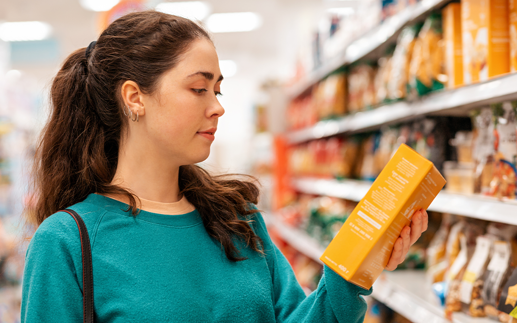 Woman in blue shirt holding a product in a grocery store - Time for a Packaging Refresh? Here's What Food & Beverage Brands Should Consider