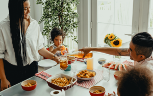 Man pouring tea in a glass a woman in holding over a dining table with two kids at the table | Leveraging Taste Related Ad Claims When Expectations are Low