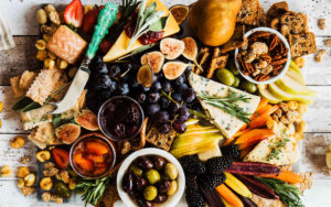 Photo of a charcuterie board from overhead. Various veggies, fruits and meats laid out on marble board | Food and Beverage Trends: Looking Ahead to 2023